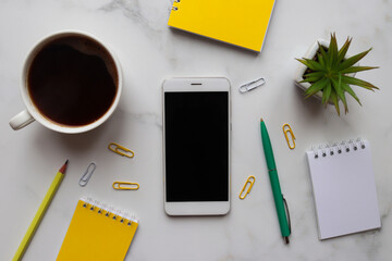 Workspace organization. Morning concept, start of work. Trendy workplace with notepads, smartphone, coffee, pencil, pen, and succulent plant on marble background. Top view, flat lay