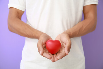 Man holding figure of heart on color background