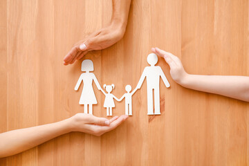 Fototapeta na wymiar Hands of family with human figures on wooden background