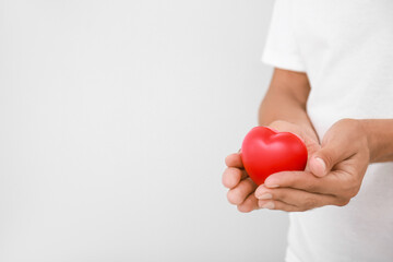 Male hands with heart on light background.