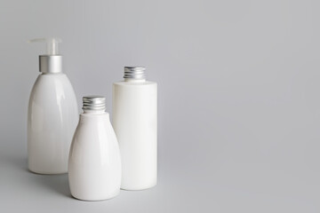 Different bottles of cosmetic products on gray background