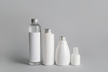Different bottles of cosmetic products on gray background