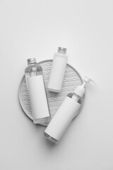 Different bottles of cosmetic products on light background