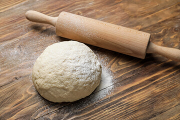 Fototapeta na wymiar Fresh dough and rolling pin on wooden background