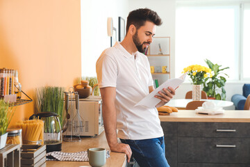 Young man reading magazine in kitchen