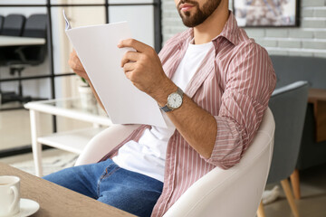 Young man reading magazine at home