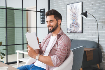 Young man reading magazine at home
