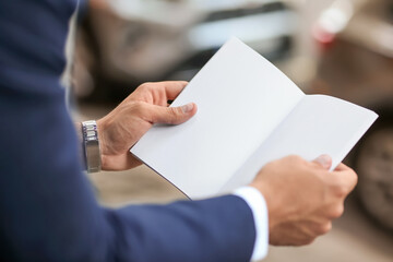 Young businessman with blank magazine outdoors