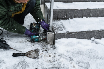 雪降りの中での玄関外階段手摺取り付け工事ベースプレート取り付け