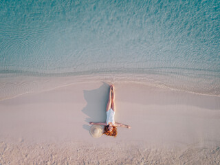 A young red-haired woman in a swimsuit lies on beach and enjoys a vacation. Top view.