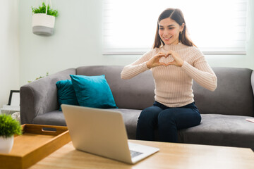 Beautiful woman making a heart with her hands in a video chat