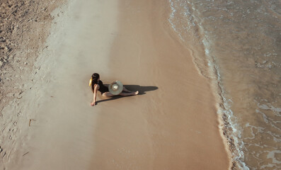 mujer sentada en la playa frente a las olas del mar