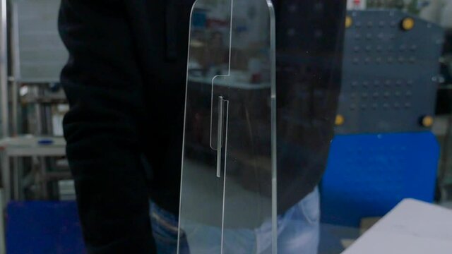 worker placing plexiglas on the table to space people