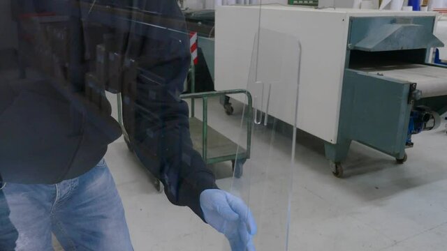 worker taking measures to put plexiglas on the table - social distancing