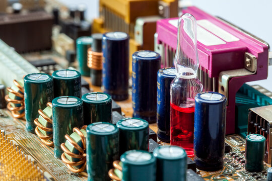 glass ampoule with a vaccine in the motherboard among the details of microelectronics close-up, a concept on the theme of chipping conspiracy theory.