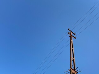 Fototapeta premium Electricity transmission tower with wires and blue sky background