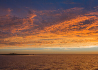 Fototapeta na wymiar Vista de paisaje de mar y cielo con nubes iluminadas de colores naranja y dorado del atardecer y amanecer 