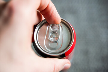 Pulling the tab of a beverage can with a left male hand. Opening a refreshment drink like cola or...