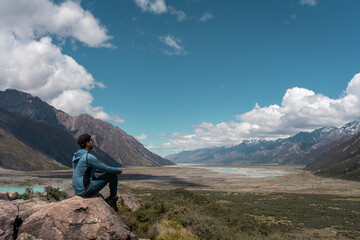Man sitting on a rock looking at the amazing view of the valley in Mount Cook National park