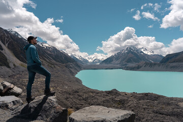 Man standing on a rock and looking at landscape in Tasman lake and mount. New Zealand