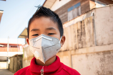 Asian children boy wear N95 mask to protect PM 2.5 dust and air pollution.