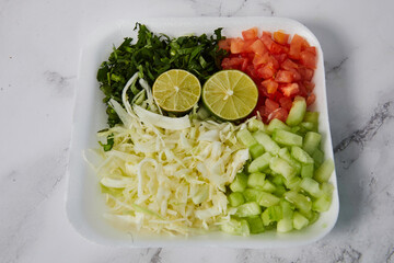 Plate of vegetables, tomato, cucumber, coriander and lemon