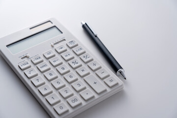 A calculator and pen on a white background