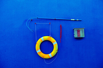 Swimming pool rescue tools hanging on the wall for emergency use only.