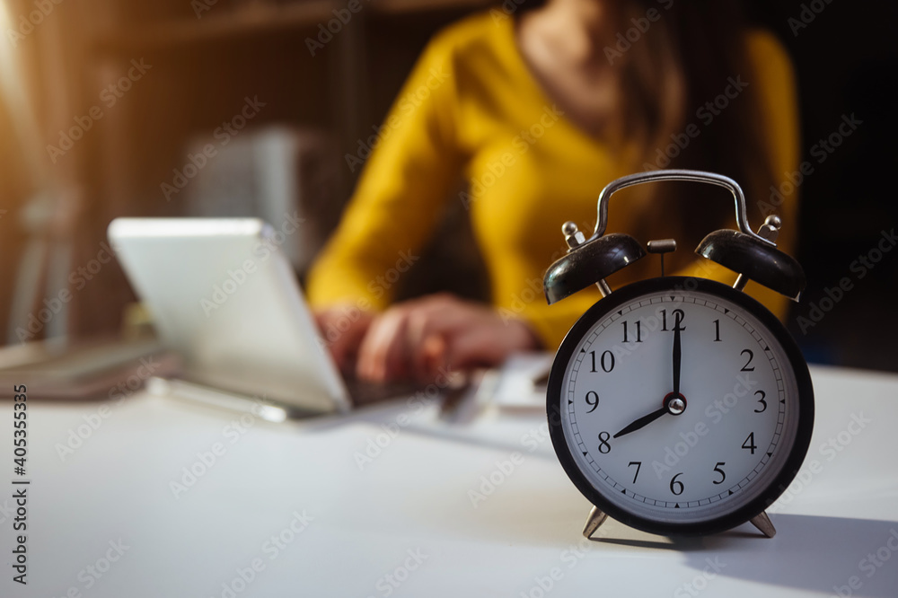 Wall mural alarm clock on the desk. business working in modern office building or home at night using laptop.. 