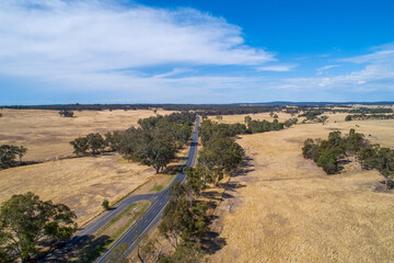 Rural highway passing through grasslands in Australian outback on sunny day