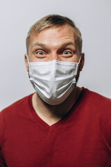 portrait of a smiling man of European appearance in a medical mask on a light background