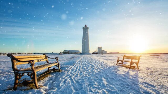 Slow motion of falling snow with benches and lighthouse on background, Iceland. Falling snow Filmed on high speed cinema camera, 1000fps. Photography on background.