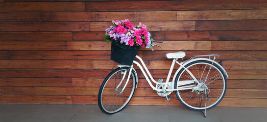 Fototapeta na wymiar Bicycle with a flower basket in pastel colours isolated with wooden background