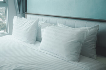 Fototapeta na wymiar White pillows and duvet on the white bed.
