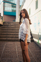 Fototapeta premium A shallow focus of an adult female wearing a white lace shirt with shorts and posing in an alle