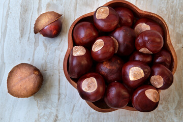 Buckeye Chestnut in wooden bowl on marble surface. Top View formation of Fresh conkers.