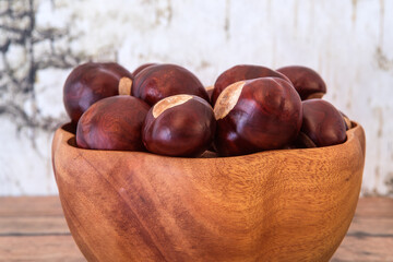 Buckeye Chestnut in wooden bowl on wooden surface. Side View formation of Fresh conkers.