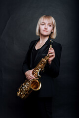 Portrait of professional musician saxophonist woman on black background