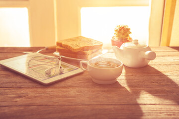Digital tablet and cup of coffee on old wooden desk.