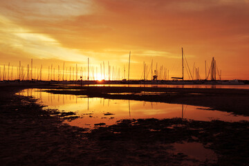 Fototapeta na wymiar Silhouetted sailboats on orange color seascape over sunset sky.