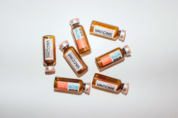 Ampules of different coronavirus vaccine lie randomly on white lab table, close-up. Covid-19 background with copy space. Development of antiviral drug. Mass vaccination of population concept.