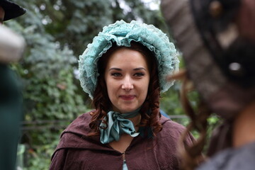 A girl in a 19th century outfit walks in the park