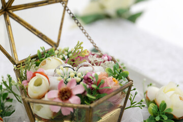 Wedding rings of the bride and groom with decorative glass box and flower. The wedding ring is decorated with flowers and a glass box for wedding rings. Wedding preparation holy matrimony