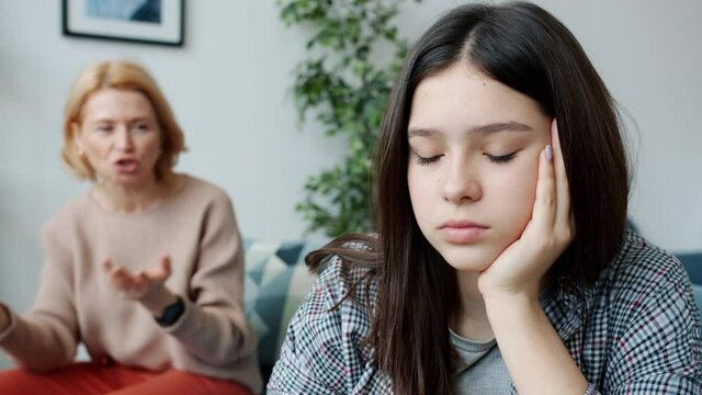 Teenager pretty girl is feeling sad and depressed when mother is lecturing her talking yelling in apartment. Relations and negative emotions concept.