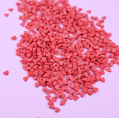 red confectionery confetti in the shape of hearts on pink background