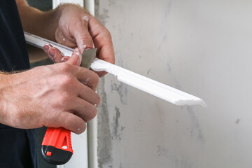 Worker fixes the plastic molding to the ceiling. Installation of ceiling cornice.