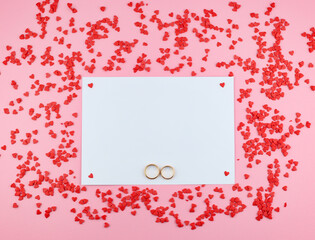wedding rings, white copy space on pink background with hearts