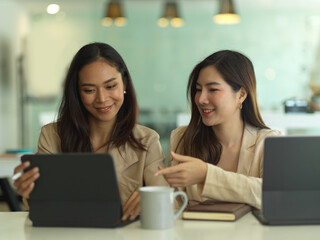Two businesswomen talking to each other while working in meeting room