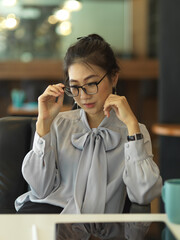 Businesswoman taking off her eyeglasses to relaxing from work in office room