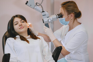 Woman patient in the medical office. Doctor in medical mask. Lor checks the woman' ears.